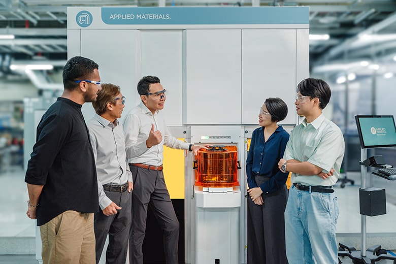 employees standing next to Applied Materials System